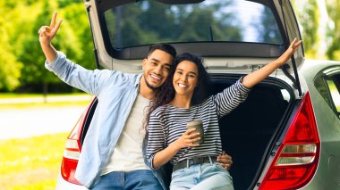 Mutlu aşıklar kameraya sarılıp gülümserken kahve içip el kaldırıyorlar. Neşeli orta doğu çifti araba yolculuğunun tadını çıkarıyor, bagajda dinleniyorlar.