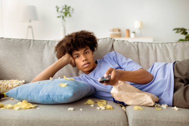 Tembel zenci genç adam kanepeye yayılmış abur cuburlarla uzanıp uzaktan kumandayla evde televizyon seyrediyor. Sıkıcı Afro-Amerikan gençliği kapalı tutulma sırasında evde sıkıcı bir gün geçiriyor