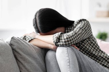 Üzgün genç bir kadın kanepede oturup ağlıyor, oturma odasının içi, fotokopi odası. Depresyondaki esmer kadın yalnızlık çekiyor, evde yalnız kalıyor, sevgilisinden ayrılıyor ya da kendini kötü hissediyor.