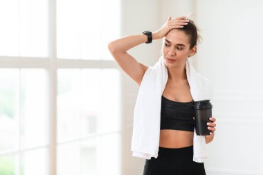 Eğitimden sonra. Boynunda beyaz havluyla yorgun genç bir kadın. Alnından ter damlayan titretici tutuyordu. Eğitimden sonra evde ya da spor salonunda dinleniyordu.