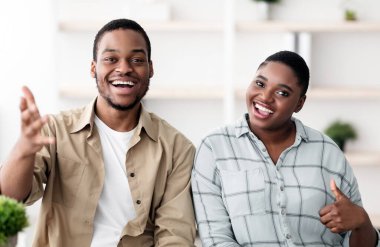 Neşeli siyah çift konuşuyor ve kameraya gülümsüyor parmaklarını hareket ettiriyor evde oturan internet üzerinden iletişim kuruyor. Mutlu müşterilerin portresi gibi. Seçici Odaklanma