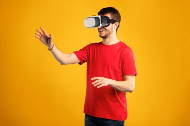 Heyecanlı sakallı adam VR kulaklık kullanıyor ve sanal gerçekliği tecrübe ediyor, mavi stüdyo duvarında izole edilmiş.