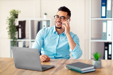 Resmi olarak yakışıklı genç bir Arap akıllı telefondan konuşur, iş yerinde sohbet etmekten zevk alır. Ofiste dizüstü bilgisayarla çalışırken müşteriyle konuşan çekici bin yıllık girişimci.