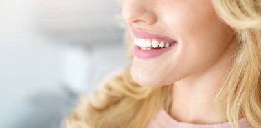 Tanınmayan sarışın bayanın güzel, sağlıklı gülümsemesini, sahnelenmiş panoramasını yan görüntüsü. Kürsüde oturan ve dişçisini tavsiye eden kadın bir diş hekimi.