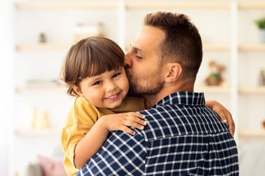 İçerde genç ve mutlu bir babanın sevimli oğlunu öperken çekilmiş bir portresi. İç mekanda birlikte vakit geçirirken, elinde çocuk taşıyan bir adam.