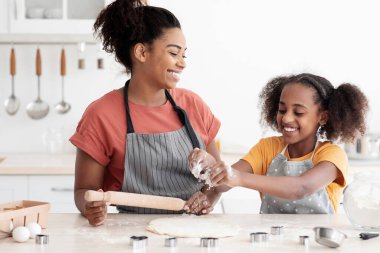 Neşeli Afro-Amerikan anne ve kızı evde birlikte yemek pişiriyor, kurabiye yapıyor ve hoş sohbetler yapıyor, harmanlıyor ve hamuru yuvarlıyor, birlikte hafta sonunun tadını çıkarıyor, uzayı kopyalıyor.