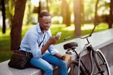 Yeşil Park 'ta cep telefonu kullanan bisikletli ve kahveli siyahi bir adam.