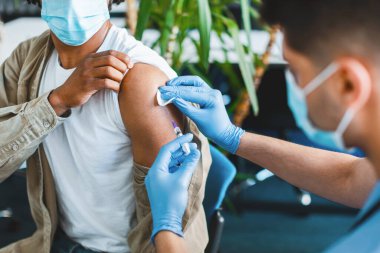 Aşı, bağışıklık sistemi, Hastalık Önleme Konsepti. Hastanede grip veya grip aşısı olan yüzü maskeli Afro-Amerikan bir adama yakın çekim. Profesyonel doktor hastaya antiviral iğne yapıyor.