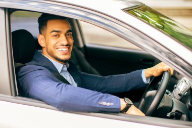 Zengin, orta doğulu, şık takım elbiseli bir işadamının resmi. Güzel bir araba sürüyor, ofise gidiyor, önemli bir iş görüşmesi yapıyor, pencereden bakıyor ve kameraya gülümsüyor..