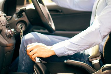 Emniyet kemerini takıp yeni rahat bir araba kullanan tanınmamış bir işadamı, el ele tutuşmuş ve direksiyon, yan görüş. Yepyeni bir arabanın içinde oturan bir şoför. Güvenli sürüş