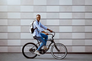 Kentin caddesinde bisiklet süren kendine güvenen Afro-Amerikan bir adamın tam boy portresi.