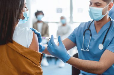 Grip aşısı kampanyası. Koronavirüs aşısı olan Asyalı kadın, hastanede doktorla otururken koluna enjekte edildi. Corona Virüsü Bağışıklık Sistemi, Tedavi ve Tedavi