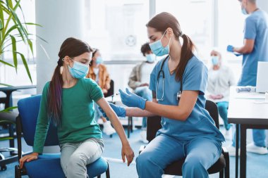 Coronavirus bağışıklığı, grip aşısı. Klinikte çocuk aşılayan doktor. Grip aşısı olan küçük bir kız. Çocuk doktoru çocuğu muayene ediyor ve iğne yapıyor. Corona virüsünün önlenmesi. Sağlık hizmetleri