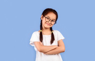 Gözlüklü küçük Çinli kız Pastel Mor Arkaplan 'ın üzerinde durup kameraya bakıyor. Stüdyo Çekimi