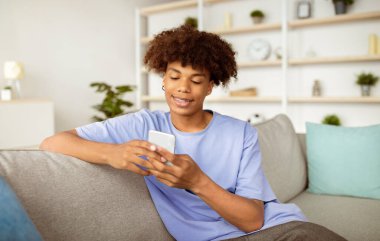 Havalı siyahi ergen cep telefonuyla internetten ders çalışıyor, arkadaşlarıyla sohbet ediyor, sosyal medyada evden paylaşıyor. Afrikalı Amerikalı ergen öğretmeniyle internette konuşuyor, konferansa katılıyor.