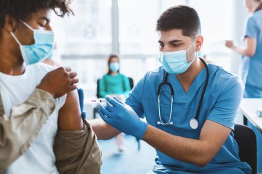 Bağışıklık, Önleme Prosedürü Konsepti. Tıp Merkezi 'nde doktor randevusu sırasında omzundan vurularak kas içi enjeksiyon yapılan Afrikalı adamın yakın çekimi.