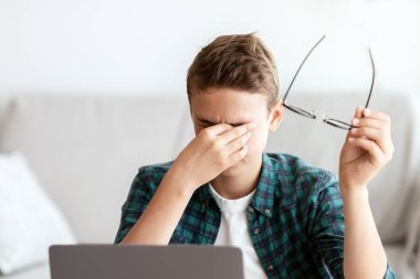 Evde ders çalışmaktan, gözlerini ovmaktan, gözlük tutmaktan, fotokopi çekmekten bıkmış bir öğrenci.