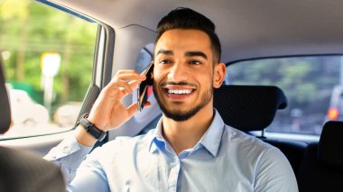 Neşeli bir ortadoğulu genç adam yönetici ofise arabayla giderken iş ortağıyla konuşuyor, arka koltukta oturuyor, yakın plan portre çekiyor. İş adamı yaşam tarzı konsepti