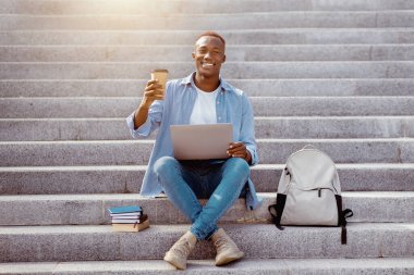 Çevrimiçi iletişim. Dışarıdaki merdivenlerde internetten biriyle konuşan Afro-Amerikalı genç bir adam.