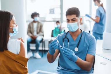 Genç Asyalı bir bayan için şırınga dolduran bir şişe grip aşısı tutan bir tıp çalışanı. İlaç alıyor. Sağlık merkezinde kitle aşılama programı. Corona virüsü önleme, koruma