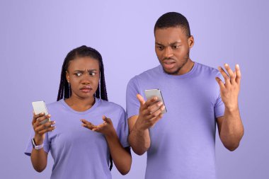 Garip Mesaj, Kötü Haber, İnternet Bağlantısı Sorunu. Kafası karışmış binlerce yıllık Afrika kökenli Amerikalı çift telefonlarına bakıyor ve omuzlarını silkiyor, mor menekşe arka planda tek başlarına duruyorlar.