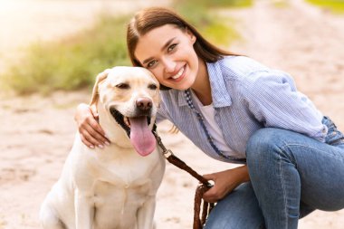 Hayvan eğitmeni konsepti. Labrador 'u olan çekici genç bir kadın dışarıda vakit geçiriyor.