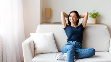 Rahatlamış kız evde koltukta oturmuş el ele tutuşuyor. Haftasonu Rahatlama Konsepti. Boşluğu Kopyala