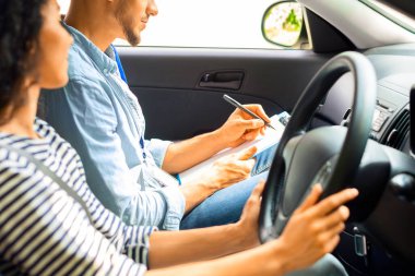 Yakışıklı Arap erkek eğitmen, esmer kız öğrenciyi muayene ediyor, çizelgeye not alıyor, gülümseyen genç bir bayanın yanında oturuyor ve test sonuçlarını bekliyor, yan görüş, kopyalama alanı.