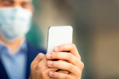 Modern akıllı telefon Arap işadamlarının elinde koruyucu yüz maskesi takan adam, girişimci, bağımsız müteahhit COVID-19 salgını, kopyalama alanı. İş dünyasındaki teknolojiler