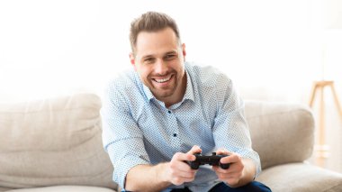 Hafta sonu vakti. Konsol kullanan gülümseyen adam rahat koltukta oturuyor, boşluğu kopyalıyor.