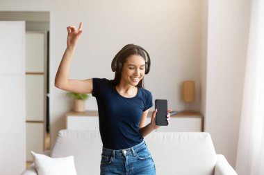 Müzik aşığı. Kulaklıklı kadın şarkı dinleyip dans ediyor ve evde eğleniyor.