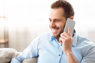 Hoş sohbetti. Gülümseyen adamın yakın plan portresi. Telefon görüşmesi yapıyor. Evde vakit geçiriyor.