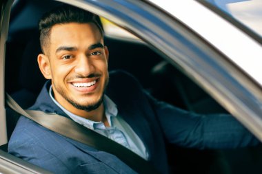 Gülümseyen orta doğulu genç iş adamının portresi. Araba sürüyor, ofise gidiyor, dışarıdan vuruluyor, yakın plan. Takım elbiseli başarılı Arap adam iyi bir günden sonra evine dönüyor.