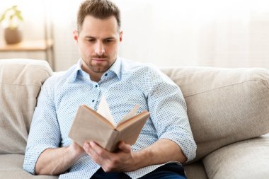 Boş zaman kavramı. Kitap okuyan yakışıklı bir adam, rahat bir koltukta oturuyor, boş yer var.