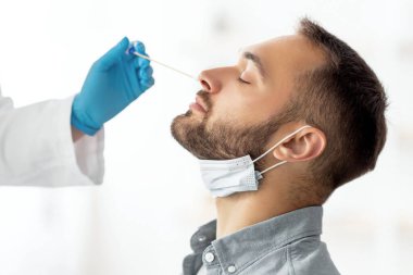 Coronavirus test prosedürü. Doktor, evdeki çubukla milenyum çocuğu için nazal PCR testi yapıyor. Genç beyaz adam koronavirüs teşhisi yapıyor. Sağlık hizmeti kavramı