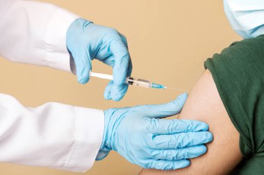 Klinikteki Arap adam için koronavirüs aşısı yapan hemşire koruyucu yüz maskesi takan hasta, yakın plan, şırınga aşısı yapan Hintli genç adam COVID-19 salgını