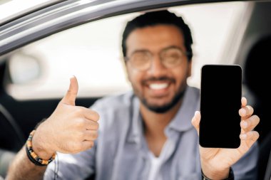 Mutlu Arap şoför elinde boş ekranlı cep telefonu tutuyor, maket. Gülümseyen orta doğulu adamın elinde boş ekran ile cep telefonunun kapanması, navigasyon için mobil uygulama, kopyalama alanı