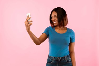 Smartphone 'da Selfie Çeken Mutlu Siyah Kadın Sarı Stüdyo Arkaplanında Duruyor. Sosyal Medya, İnsanlar ve Gadget Kavramı. Modern Yaşam Tarzı ve Teknoloji