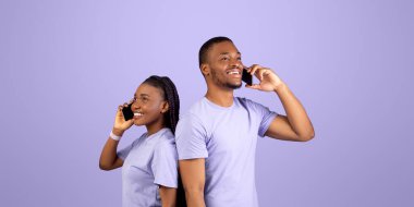 Sırt sırta duran neşeli Afro-Amerikan çiftin portresi, cep telefonlarıyla konuşan sevgililer, Violet stüdyosunun arka planında izole edilmiş, bedava fotokopi alanı. İyi Bağlantı