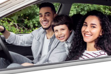 Gülümseyen genç Arap adam ve çocuklu kadın arabaya biniyor ve açık pencereden, açık pencereden, manzaradan kameraya bakıyorlar. Yazın ailenle seyahat et, yol ve tatilde birlikte otomobille seyahat et.