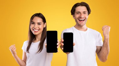 Yeni Mobil Uygulama Üzerine Heyecanlı. Tasarım, evet hareketi, reklam sitesi, afiş için siyah ekranlı iki akıllı telefonu tutan neşeli genç adam ve kadının portresi