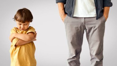 Çocuk kaprisleri. Elleri çapraz duran, babasına kırgın olan, elleri beyaz duvara karşı ceplerinde duran, tanınmayacak kadar ilgisiz bir çocuk.