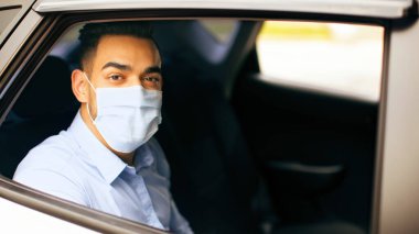 Orta Doğulu koruyucu maskeli genç girişimci takside oturuyor, ofise giderken COVID-19 salgını, yakın plan portresi, kopyalama alanı. Arap işadamı iş toplantısına gidiyor