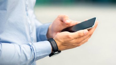 Tanımlanamayan işadamı ofis merkezinde duruyor, elinde boş ekranlı modern akıllı telefonu tutuyor, iş sürecini internetten kontrol ediyor, mobil iş uygulaması kullanıyor, kapatıyor, boşluk kopyalıyor.