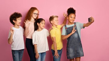 Çok uluslu öğrenciler pembe arka planda selfie çekiyorlar.