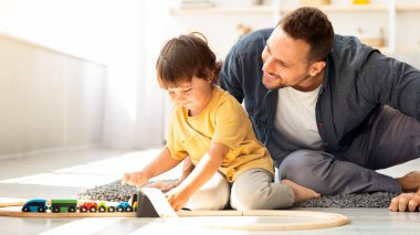 Mutlu oyun zamanları. Sevgi dolu babasıyla ahşap tren ve demiryolu oyunu oynayan, evde birlikte oturan, boş bir yer.