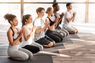 Yoga dersi. Nilüfer çiçeği jesti yapan ve stüdyoda birlikte meditasyon yapan bir grup genç.