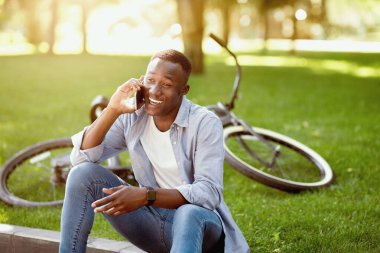Modern motosikletli çekici siyahi adam Green Park 'ta cep telefonuyla konuşuyor. Mesaj için yer var.