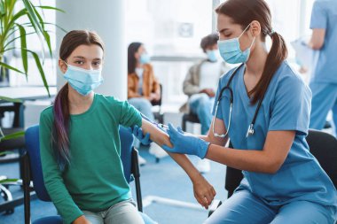 Toplu Virüs Bağışıklık Kampanyası. Corona 'ya grip aşısı ya da grip aşısı olan genç aşısı olan bir kadın. Hastanenin iç kısmında, kolunda otururken vuruldu. Coronavirus Aşılama Noktası