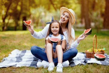 Yaz pikniği. Anne ve Kız Yeşil Park 'ın dışında karpuz yiyen meyvelerle poz veriyorlar..